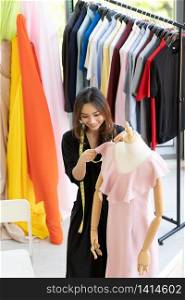 Top view of young adult asian fashion designer using measuring tape to measure dress arm at her atelier studio as sole owner. Using for entrepreneur small business startup concept.