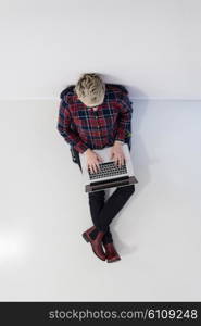 top view of young business woman working on laptop computer in modern bright startup office interior, sitting on floor