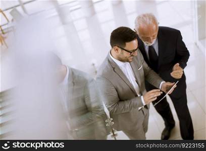 Top view  of young businessman pointing and showing something to senior partner on digital tablet at office