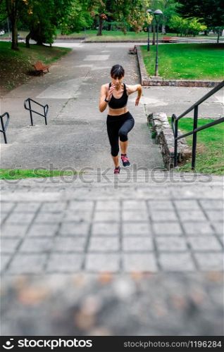 Top view of young female athlete training climbing stairs outdoors. Female athlete climbing stairs outdoors