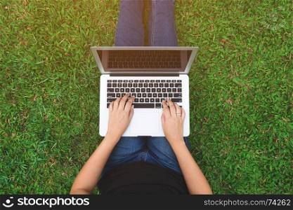 top view of young woman using laptop on a grass