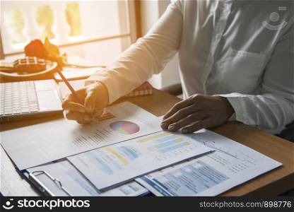Top view of young working woman using laptop and reading report , graphs , charts, document at work. Business woman working at her desk.