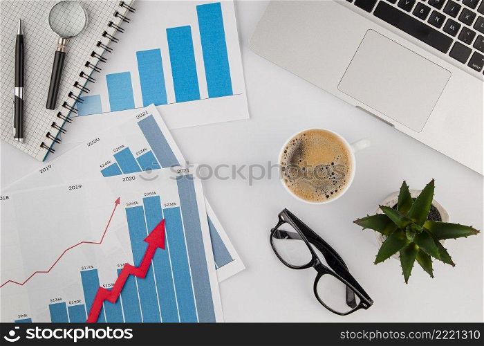 top view office desk with growth chart coffee with glasses