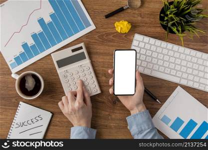top view office desk with growth chart hands using calculator
