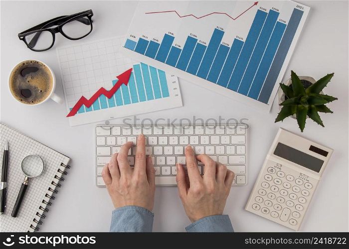 top view office desk with growth chart hands using keyboard