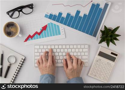 top view office desk with growth chart hands using keyboard