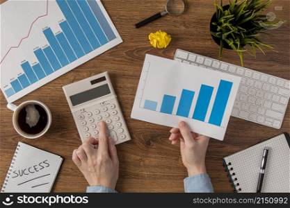 top view office desk with growth chart hands using tiny calculator