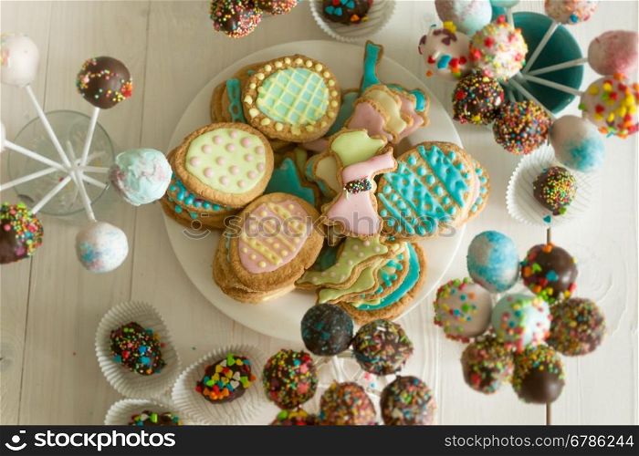 Top view on assortment of candies, cake pops and cookies on wooden table at confectionery