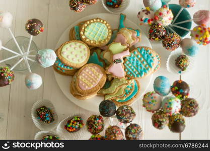 Top view on assortment of candies, cake pops and cookies on wooden table at confectionery