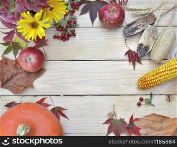 top view on colorful autumnal still life on with seasonal food and flowers on a wooden table with copy space at the middle