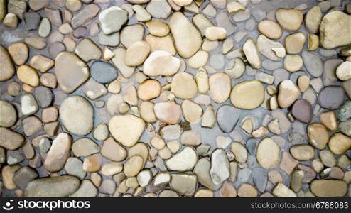 Top view on colorful pebbles covered by river water