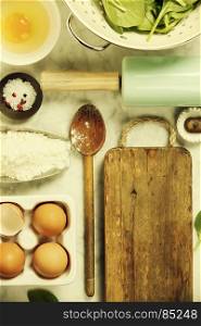 Top view on cooking ingredients and vintage kitchen accessories on old marble table