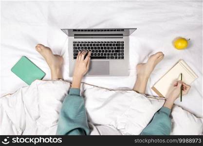 Top view on female hands holding pen and working on modern laptop from home. Home office or online education concept. Top view on female hands holding pen and working on modern laptop from home. Home office or online education concept.