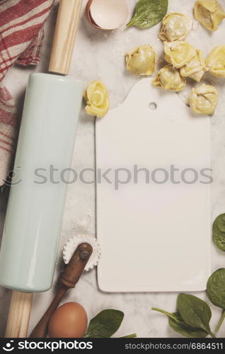 Top view on homemade pasta ravioli on old table with ingredients and vintage kitchen accessories