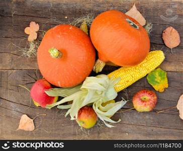 top view on pumpkins, maize and apples arranged on a wooden and rustic table
