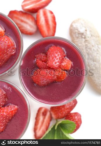 top view on red fruit coulis and strawberries in glass isolated on white background