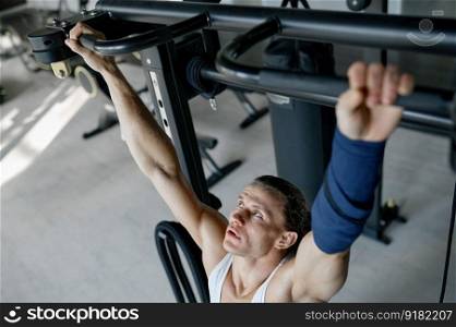 Top view on strong sportsman training with weights using gym equipment. Man with athletic body having pull up workout for bodybuilding. Top view on strong sportsman training with weights using gym equipment