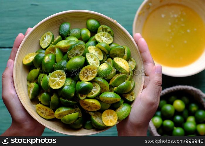 Top view people hand hold kumquat peel in green that squeezed out of fruits, this sour fruit rich vitamin c, healthy and make detox drink