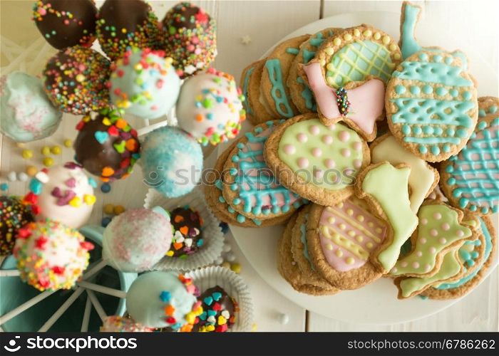 Top view photo of colorful cake pops and easter cookies on table