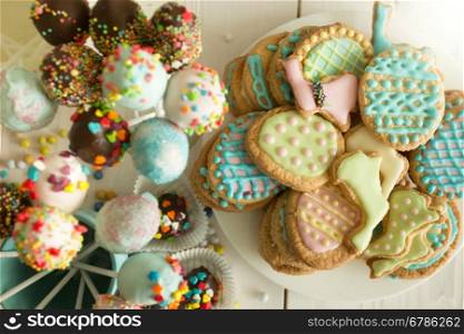 Top view photo of colorful cake pops and easter cookies on table