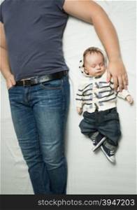 Top view photo of young stylish father and baby boy in jeans lying on bed