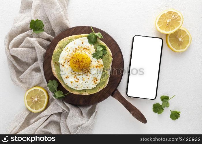 top view pita with avocado spread fried egg with blank phone