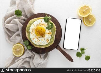 top view pita with avocado spread fried egg with blank phone