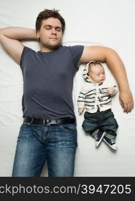 Top view portrait of stylish father and baby boy sleeping on bed