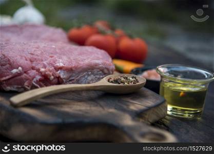 Top view raw beef meat steak ingredient uncooked cuisine on wooden board. Steak western cuisine ingredient fresh meat, pepper, olive oil, garlic, chilli, tomato, salt and rosemary outdoor for party. Western food concept