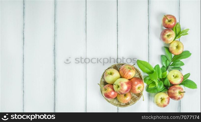 Top view red and yellow apple. Top view red and yellow apple with leaves and bamboo basket on white wooden background with free space for text