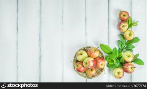 Top view red and yellow apple. Top view red and yellow apple with leaves and bamboo basket on white wooden background with free space for text