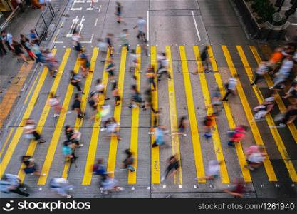 Top view scene of Motion blurred Crowd unrecognizable pedestrians crossing over the Hong Kong street around mong kok station, yellow color zebra is the sign of hong kong transportation and crosswalk