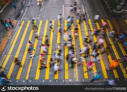 Top view scene of Motion blurred Crowd unrecognizable pedestrians crossing over the Hong Kong street around mong kok station, yellow color zebra is the sign of hong kong transportation and crosswalk