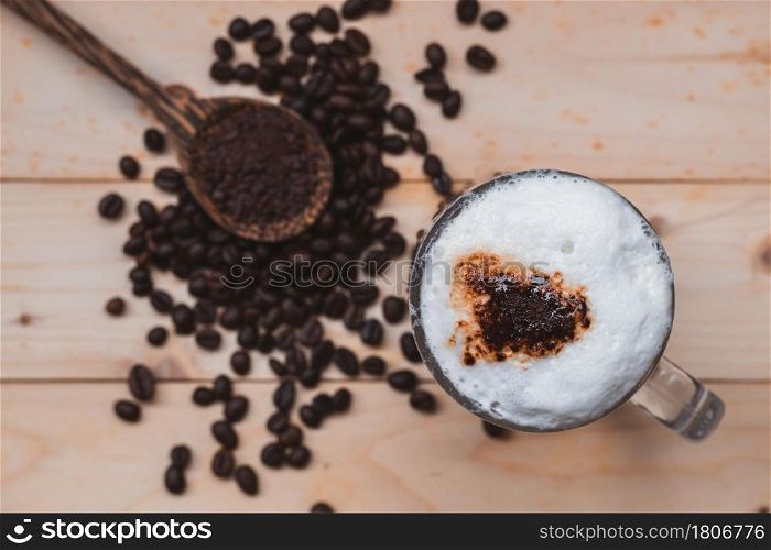 Top view selective focus of iced coffee froth in coffee mug cup on wooden floor.