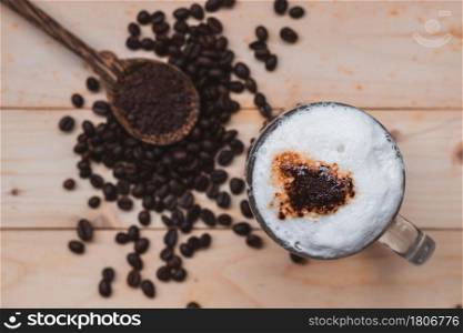 Top view selective focus of iced coffee froth in coffee mug cup on wooden floor.