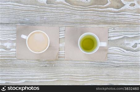Top view shot of coffee and green tea drinks on aged white wood surface in horizontal format.