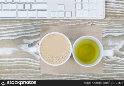 Top view shot of desktop with coffee and green tea drinks on aged white wood surface in horizontal format.