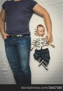 Top view shot of father and little son in jeans sleeping on bed