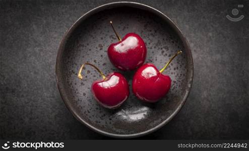 top view shot of ripe red sweet cherries in rusty ceramic plate on dark tone texture background in full hd ratio, 16x9, cherry