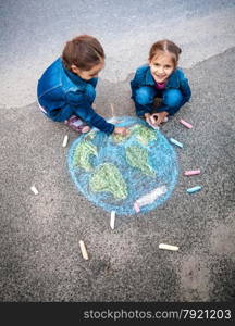 Top view shot of two girls drawing Earth with chalks