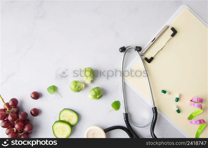 top view stethoscope with cucumber slices grapes
