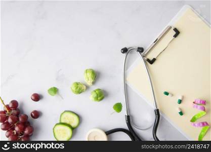 top view stethoscope with cucumber slices grapes