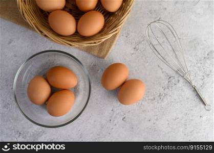 Top View three eggs in glasses bowl, blurred eggs in wicker basket and egg beater on the floor, preparing preparing for cooking food or dessert, copy space 