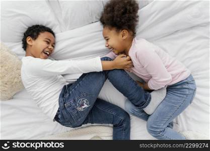 top view two siblings playing bed home together
