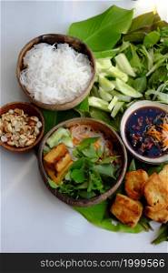 Top view vegan food ready to eat on leaf background, fried tofu, bun, cucumber and herbal leaf as mint, lettuce with soy sauce, healthy eating with vegetable make for good natural immunity