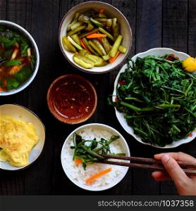 Top view vegan Vietnamese food for lunch, bowl of rice, boiled water spinach, salted cucumber, fried egg, tomato soup, homemade vegetarian meal with vegetables for vegan diet
