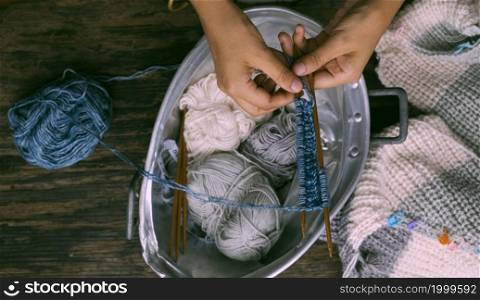 Top view, Vietnamese woman hands with ball of yarn to make winter present, female knitting woollen sweater, leisure activity, knit at home to make handicraft clothing