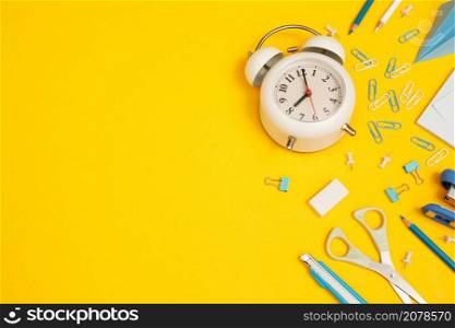 top view white alarm clock and accessories stationery studying in the library at school yellow background idea education