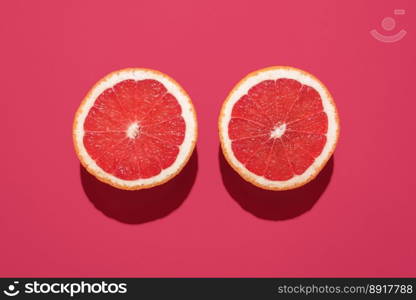 Top view with two slices of grapefruit isolated on a magenta colored background. Grapefruit sliced in half minimalist on a vibrant table