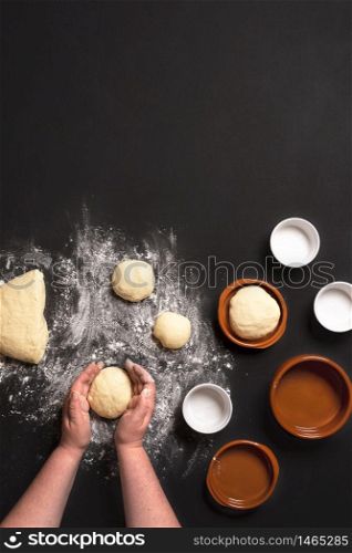 Top view with woman&rsquo;s hands shaping the dough to make bread buns. Baking bread in small round ceramic trays.